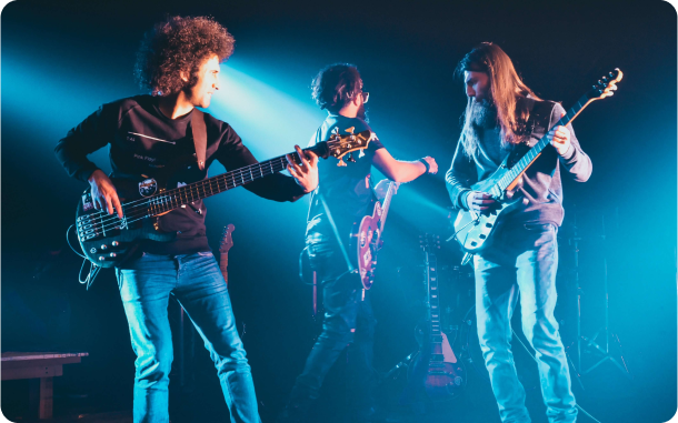 Três homens em um pauco tocando guitarras e baixo